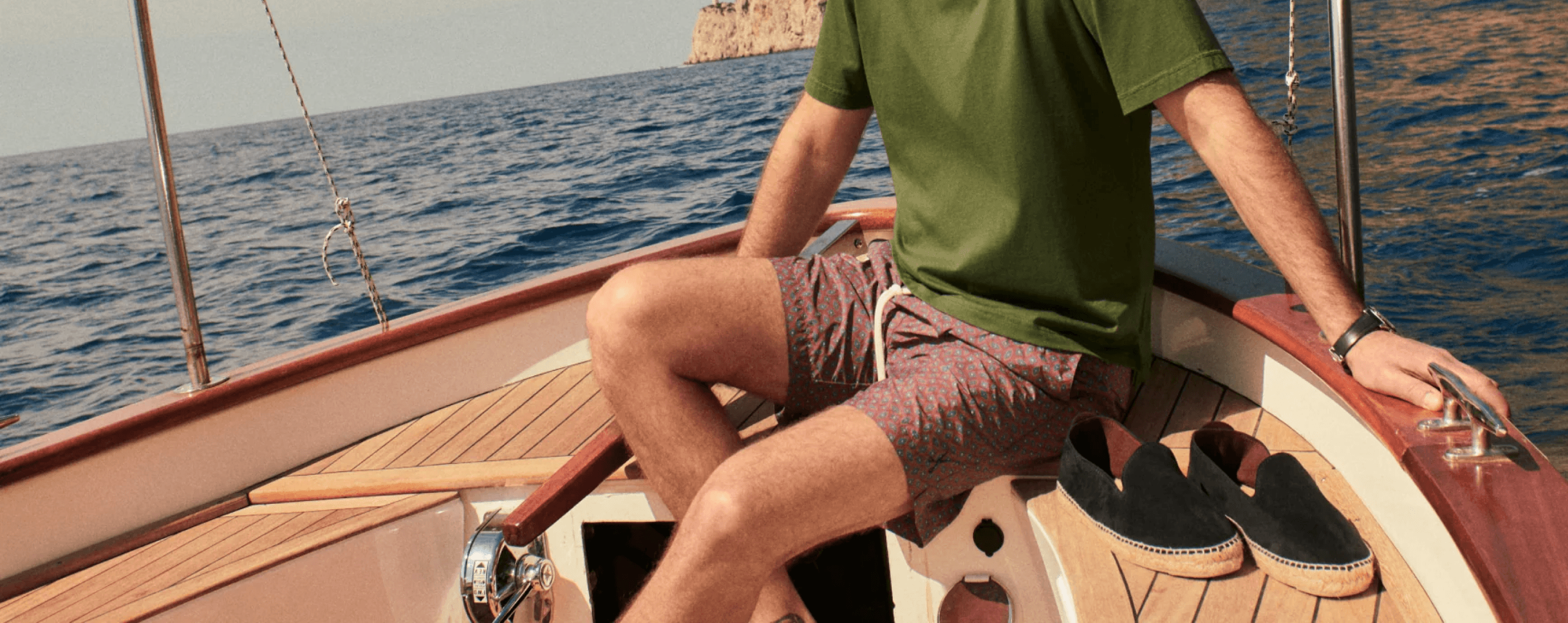 A sunlit boat with espadrilles beside a passenger at sea.