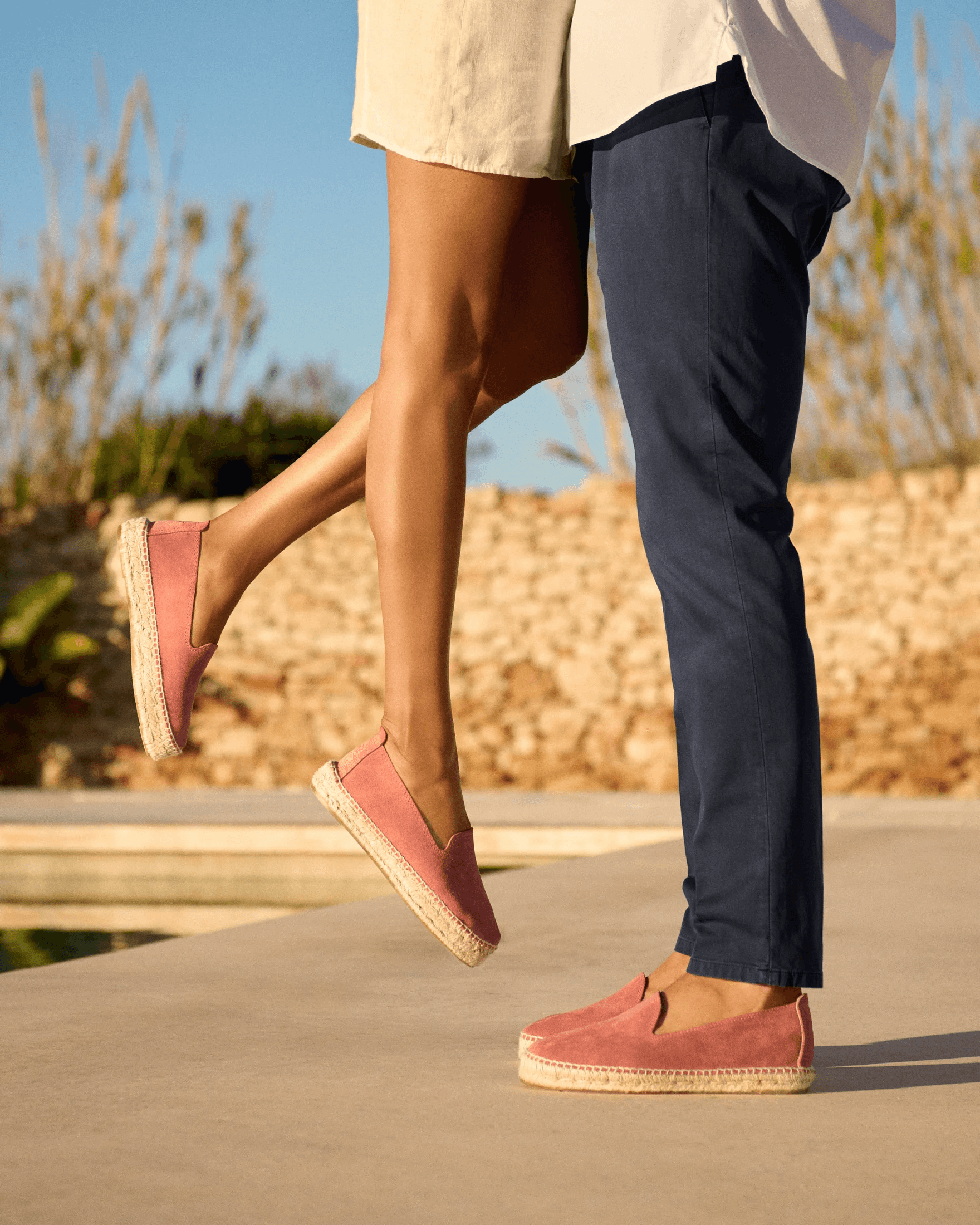 Two people wearing rose espadrilles in warm sunlight.