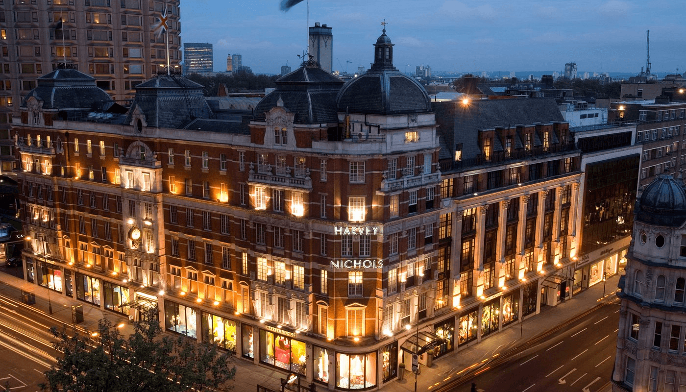 An evening city streetscape with a department store building.